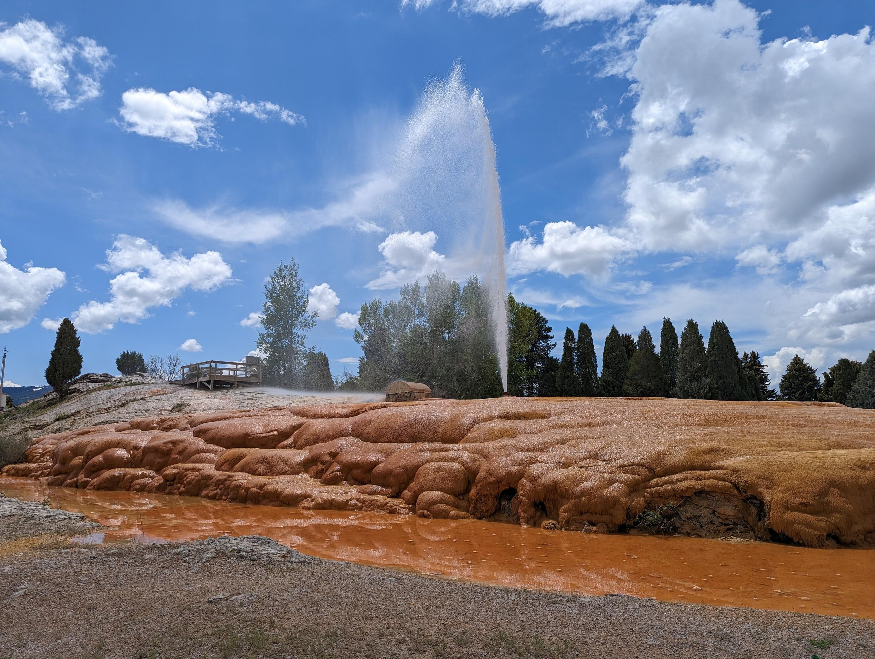 Soda Springs geyser erupting under a bright blue sky